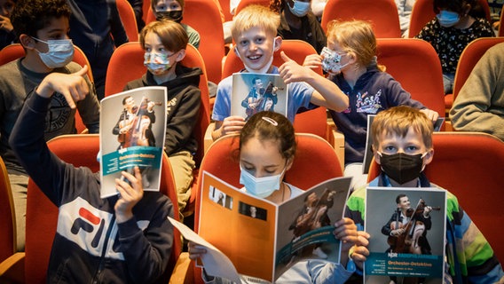 Schüler*innen im Großen Sendesaal des NDR mit Programmheften des Orchester-Detektive-Konzerts im Mai 2022 © NDR Foto: Helge Krückeberg