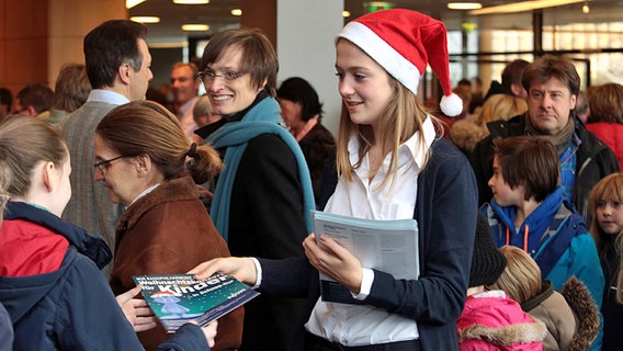 Mädchen mit Nikolausmütze verteilt Programmhefte. © NDR Foto: Michael Plümer