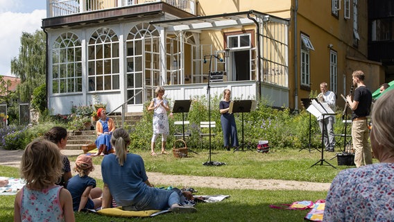 Publikum auf Picknick-Decken und Musiker*innen der NDR Radiophilharmonie im Garten der Stiftung Edelhof in Ricklingen © NDR Foto: Helge Krückeberg