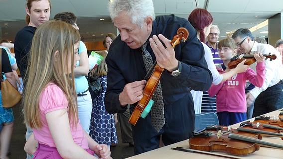 Bratschist Moshe Ben Dor erklärt einem Mädchen die Haltung der Geige, Impressionen vom Kindermusikfest der NDR Radiophilharmonie und der Musikschule Hannover am 8. Juni 2013 © NDR Radiophilharmonie Foto: Julian Zeuner