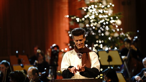 Matthias Keller vor einem Pult in der Luft wie auf einer Schreibmaschine tippend spricht Cratchit, die Geister der Weihnacht und andere © NDR Foto: Micha Neugebauer