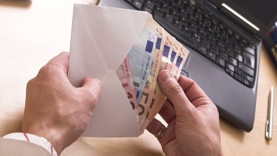 Jemand zählt Geld in einem Briefumschlag im Büro vor einem Laptop. © GaToR-GFX _Fotolia.com 