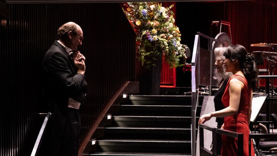 Dirigent Andrew Manze und die Pianistinnen Shin-Heae Kang und Martha Argerich stehen sich am Bühnenrand des Kuppelsaals gegenüber. © NDR / Helge Krückeberg Foto: Helge Krückeberg