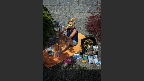 Margje Imandt, mit Schnorchelmaske im Gesicht, packt auf einer gelben Decke ihren Horn-Koffer aus © NDR Foto: François Lefèvre