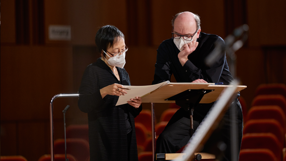 Andrew Manze, Chefdirigent der NDR Radiophilharmonie, und eine Musikerin über ein Notenbuch gebeugt © NDR Foto: Micha Neugebauer