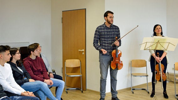 Bratscher Carlos Campos Medina spricht vor Schülerinnen und Schülern. © NDR Foto: Sophie Brunner