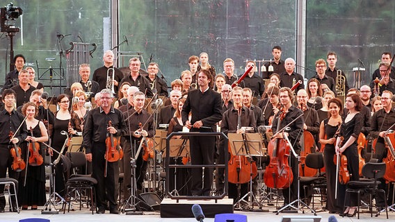 Orchester und Dirigent erheben sich zum Applaus. © Axel Herzig Foto: Axel Herzig
