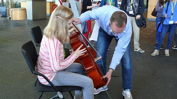 Cellist zeigt einem Mädchen sein Instrument © NDR Radiophilharmonie Foto: Corinna Lüke
