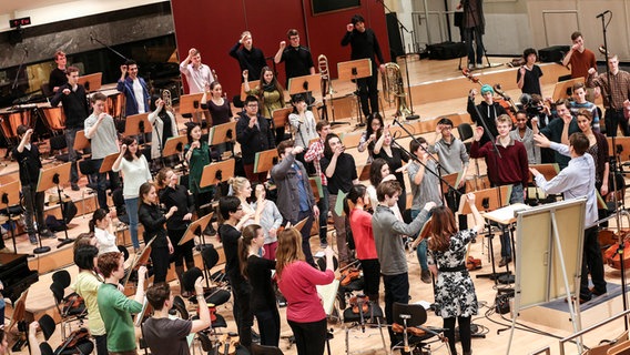 Stehende Orchestermusiker mit erhobenen Armen.  Foto: Marcus Krüger