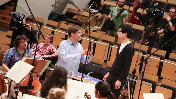 Der Dirigent spricht mit einem jungen Mann.  Foto: Marcus Krüger
