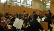 Ein Orchester spielt in der Turnhalle einer Schule. © hr Sinfonieorchester 