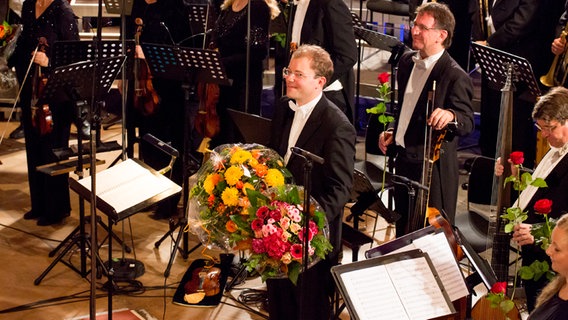 Jubiläumskonzert: Dirigent Ahmann mit zwei Blumensträußen. © NDR Foto: Claudia Timmann