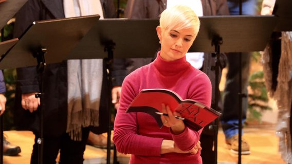 Frau mit kurzen weißblonden Haaren singt aus Noten. © NDR Foto: Kristien Daled