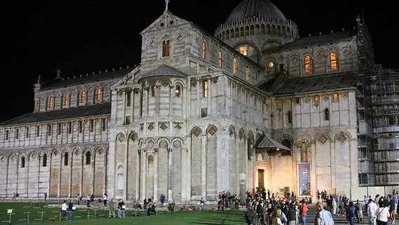 Konzertgäste stehen vor dem abendlich beleuchteten Dom von Pisa © NDR Chor 