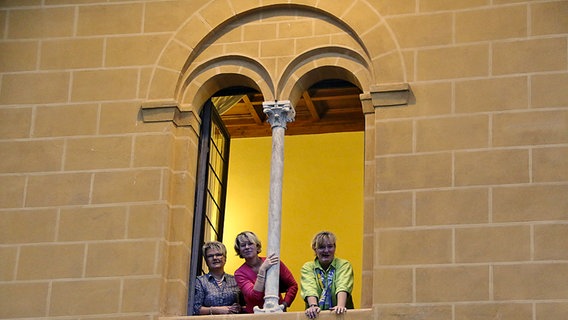 Drei Chorsängerinnen schauen aus einem Kirchenfenster © NDR Chor 