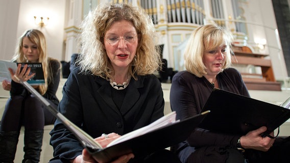Chorsängerinnen blättern vor der Orgel sitzend in ihren Noten. © NDR Foto: Dirk Uhlenbrock