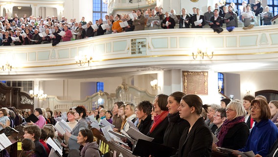 Blick von unten: Sänger und Sängerinnen mit Noten in den Kirchenbänken und auf der Empore. © NDR Foto: Dirk Uhlenbrock
