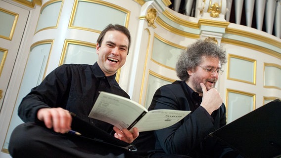 Zwei lachende Chorsänger sitzen auf den Orgelstufen © NDR Foto: Dirk Uhlenbrock