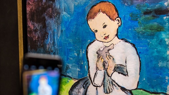 Ein Besucher fotografiert das Gemälde "born to be child" von Otto Waalkes im Caricatura Museum Frankfurt mit seinem Smartphone. © dpa Foto: Fabian Sommer