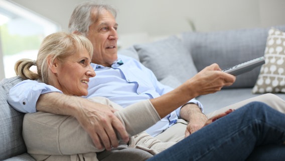 Etwas älteres Paar sitzt auf dem Sofa und schaut Fernsehen. © goodluz/fotolia Foto: goodluz