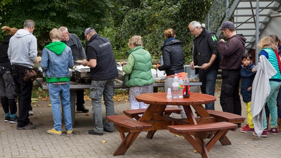 Das Filmteam steht draußen in einer Schlange um sich am aufgebauten Buffet zu bedienen. © NDR Foto: Claudia Timmann