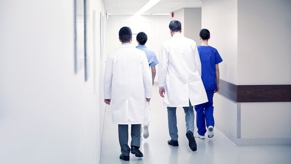 Vier Ärzte gehen in einem Krankenhausflur von hinten gesehen. © Colourbox Foto: Syda Productions