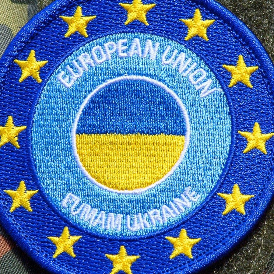 Die Deutsche Fahne und das Wappen der "European Union Military Assistance Mission in support of Ukraine" ist auf dem Truppenübungsplatz auf der Schulter eines Soldaten zu sehen. © picture alliance/dpa | Klaus-Dietmar Gabbert 