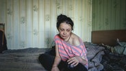 Eine Frau, deren Wohngebäude in Cherson bereits von russischen Artilleriegeschossen getroffen wurde, leidet nach fast anderthalb Jahren Krieg unter Angstzuständen und Depressionen. © picture alliance / imageBROKER | Florian Bachmeier 