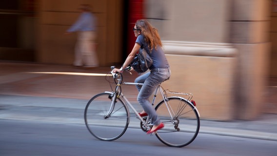 Eine Frau fährt mit einem Fahrrad auf der Straße © Picture Alliance | Photoshot Foto: Picture Alliance / Photoshot