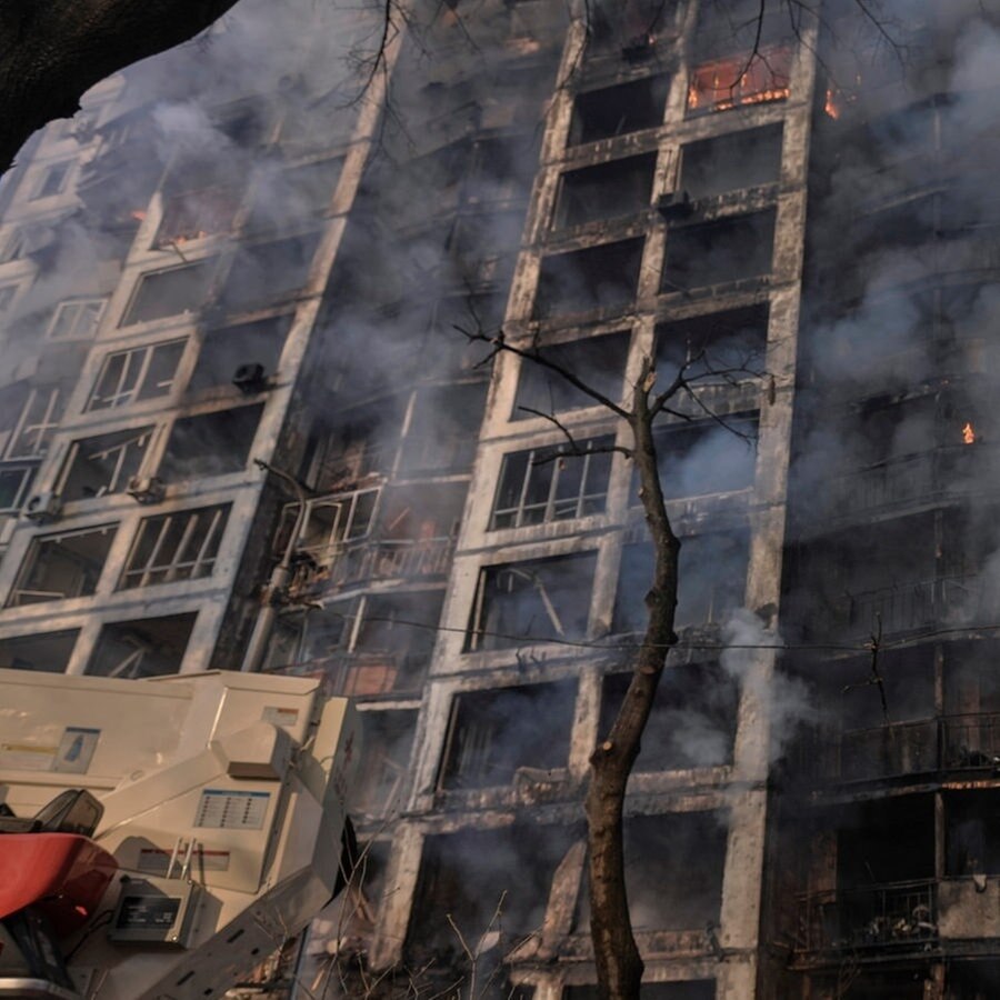 Einsatzkräfte der Feuerwehr stehen vor einem brennenden Wohngebäude, dass durch Bombenbeschuss des russischen Militärs zerstört wurde. © picture alliance/dpa/AP | Vadim Ghirda Foto: Vadim Ghirda