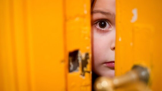 Ein kleines Mädchen schaut durch einen Türschlitz ©  Picture Alliance / dpa / Ole Spata Foto: Ole Spata