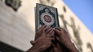 Anhänger der Volksmobilisierungskräfte halten eine Kopie des Korans. © dpa-Bildfunk Foto: Ameer Al-Mohammedawi