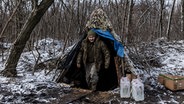 Ein ukrainischer Soldat in Charkiw verlässt sein Zelt, um ihn herum Schneetreiben. © picture alliance / Anadolu | Diego Herrera Carcedo 