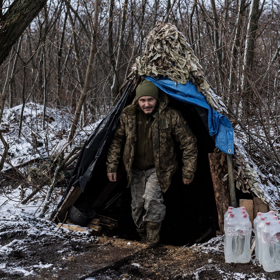 Ein ukrainischer Soldat in Charkiw verlässt sein Zelt, um ihn herum Schneetreiben. © picture alliance / Anadolu | Diego Herrera Carcedo 