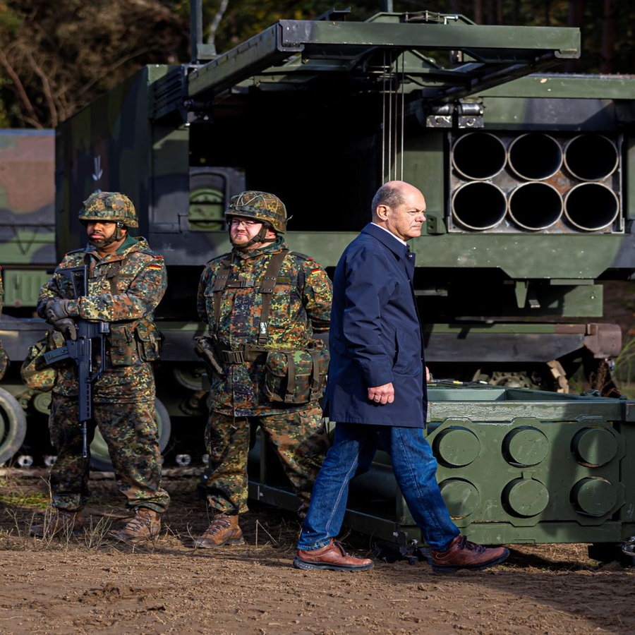 Bundeskanzler Olaf Scholz (SPD, r) geht vor der Ausbildungs- und Lehrübung des Heeres im Landkreis Heidekreis in der Lüneburger Heide vor Soldaten entlang. © picture alliance/dpa | Moritz Frankenberg 