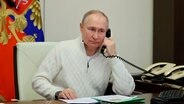 Russlands Präsident Vladimir Putin am Telefon. Hinter ihm zwei weiße ältere Telefone. © picture alliance / ASSOCIATED PRESS | Mikhail Klimentyev 