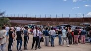 Asylsuchende stehen an der Grenze in Jacumba, Kalifornien, während ihnen Freiwillige Getränke und Snacks reichen. © picture alliance / Newscom | ARIANA DREHSLER 