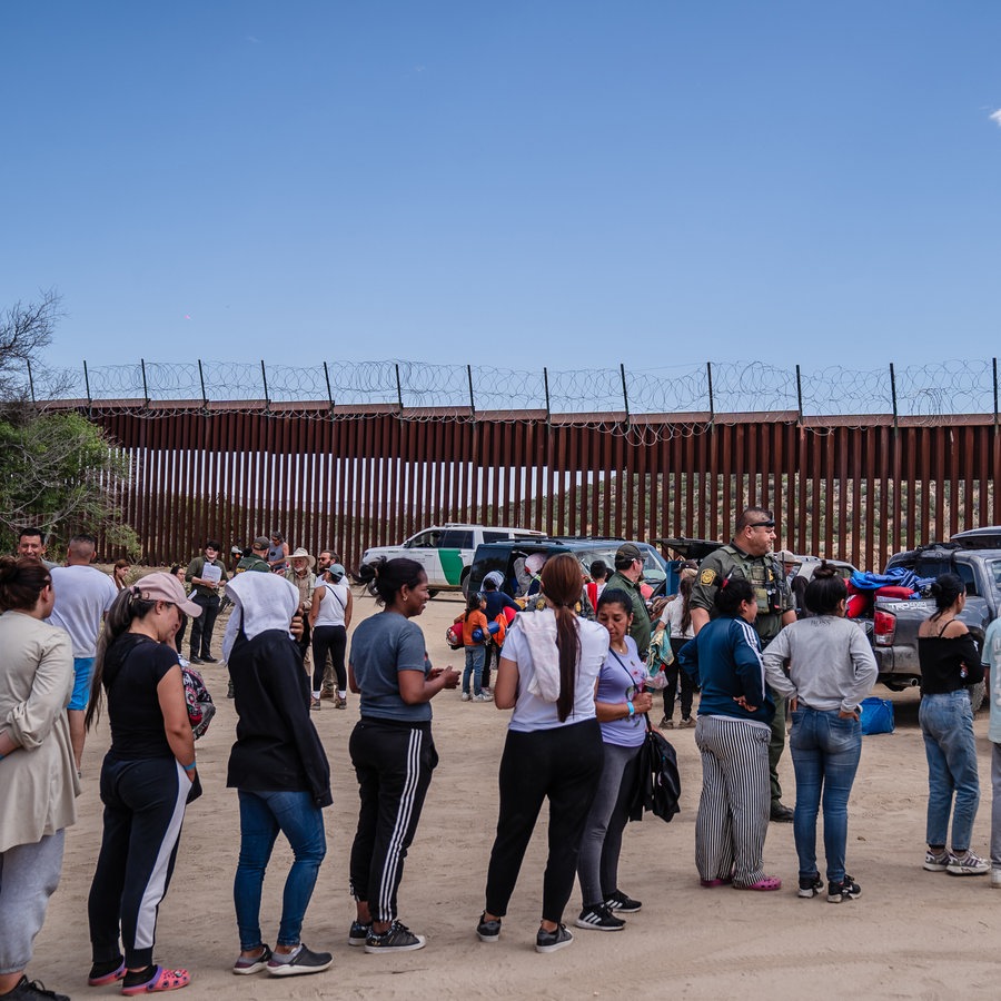 Asylsuchende stehen an der Grenze in Jacumba, Kalifornien, während ihnen Freiwillige Getränke und Snacks reichen. © picture alliance / Newscom | ARIANA DREHSLER 