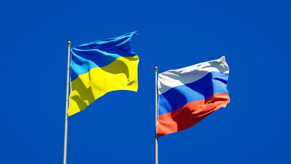 Die russische und die ukrainische Flagge wehen im Wind vor blauem Himmel © dpa picture alliance / Zoonar Foto: Leonid Altman