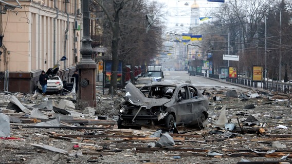 Ein ausgebranntes Auto steht auf einer von Trümmern übersäten Straße © picture alliance/dpa/Ukrinform | --- Foto: Ukrinform | ---