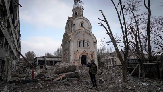 A Ukrainian soldier photographs a damaged church after a bombing in a residential area.  © dpa / AP Photo: Evgeniy Maloletka