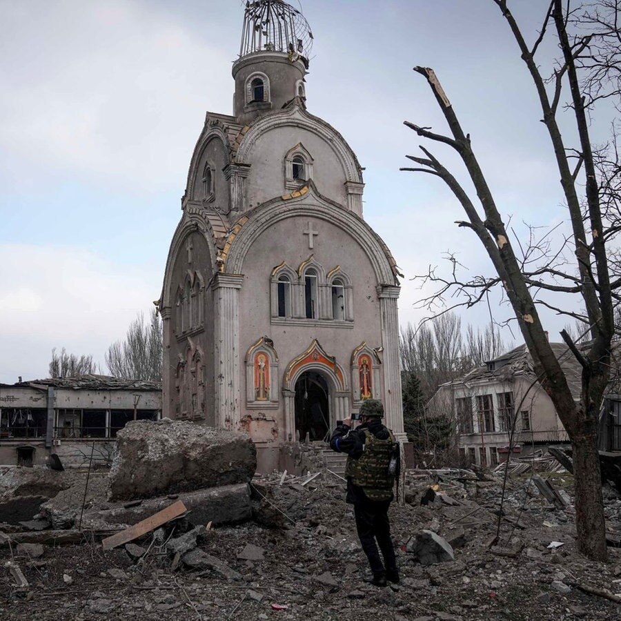 Ein ukrainischer Soldat fotografiert eine beschädigte Kirche nach dem Beschuss eines Wohnviertels. © picture alliance / ASSOCIATED PRESS | Evgeniy Maloletka Foto: Evgeniy Maloletka