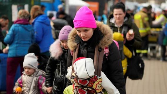 Eine Frau mit einem Baby in einem Tragegestell und zwei Kindern an der Hand © picture alliance/dpa/AP | Sergei Grits Foto: Sergei Grits