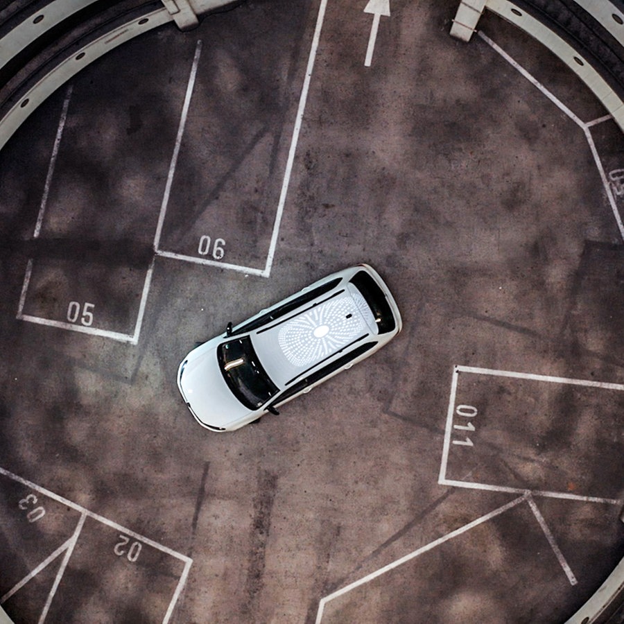 Ei Auto der Marke VW steht im Erdgeschoß eines Parkhaus von oben herab gesehen. © Lucas Stratmann und Willem Konrad 