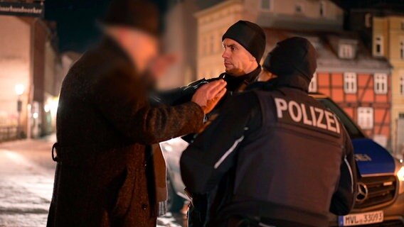 Zwei Polizisten in dunkler Altstadt von Stralsund und ein nicht erkennbarer Mann dessen Personalien kontrolliert werden. © NDR/Thomas Eichler Foto: Thomas Eichler