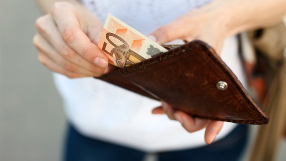 Jemand nimmt aus einem Portemonnaie Geld. © fotolia.com Foto: Andrei Korzhyts