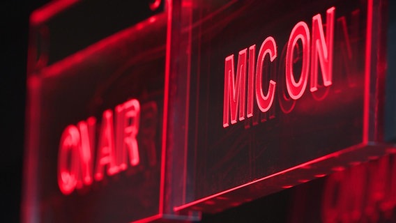 Auf zwei Leuchtschildern ist einmal "ON AIR" und "MIC ON" zu lesen. © NDR 
