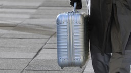 Mann transportiert Koffer im Hintergrund Gehwegplatten © panthermedia Foto: Viola B.