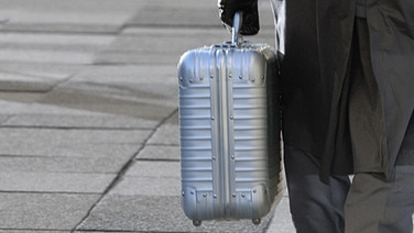 Mann transportiert Koffer im Hintergrund Gehwegplatten © panthermedia Foto: Viola B.
