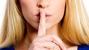Eine Frau legt ihren Zeigefinger vor den Mund © Fotolia.com Foto: Picture-Factory